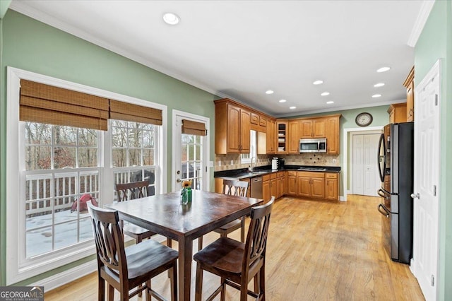 dining area with a wealth of natural light, sink, light wood-type flooring, and ornamental molding