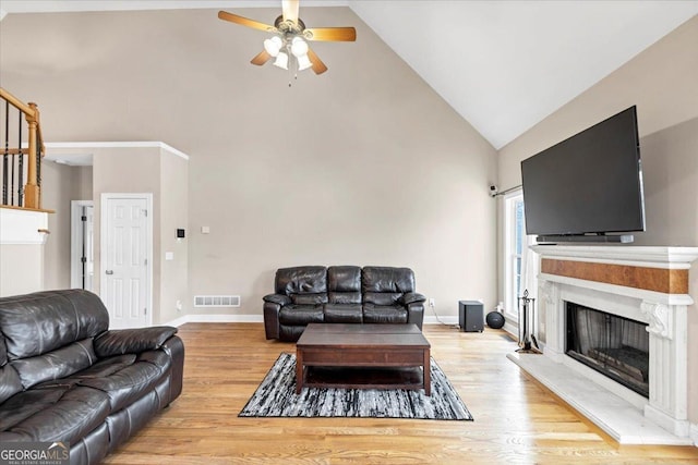 living room with ceiling fan, light hardwood / wood-style flooring, and high vaulted ceiling