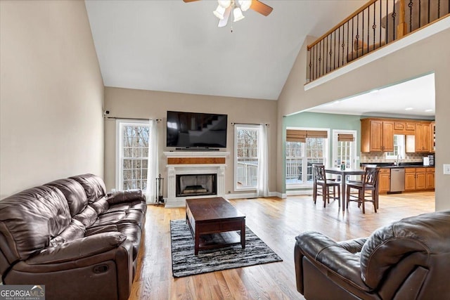 living room with a high ceiling, light wood-type flooring, ceiling fan, and sink