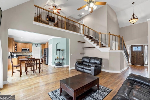 living room featuring ceiling fan, light wood-type flooring, and high vaulted ceiling