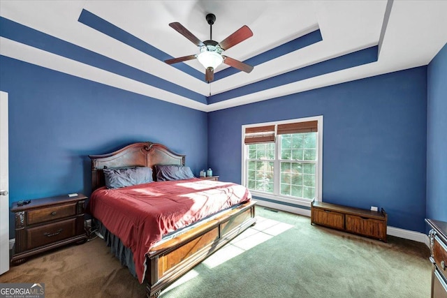 bedroom with ceiling fan, carpet floors, and a tray ceiling