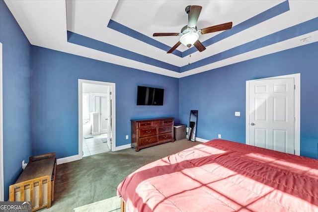 carpeted bedroom with a raised ceiling and ceiling fan