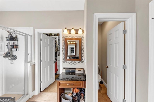 interior space featuring tile patterned flooring, vanity, toilet, and an enclosed shower