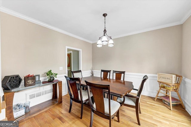 dining space with ornamental molding, light hardwood / wood-style floors, and an inviting chandelier