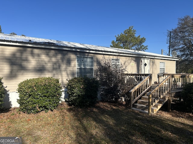 rear view of property with a wooden deck and a lawn