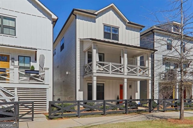 view of front of house featuring a fenced front yard, a balcony, and board and batten siding