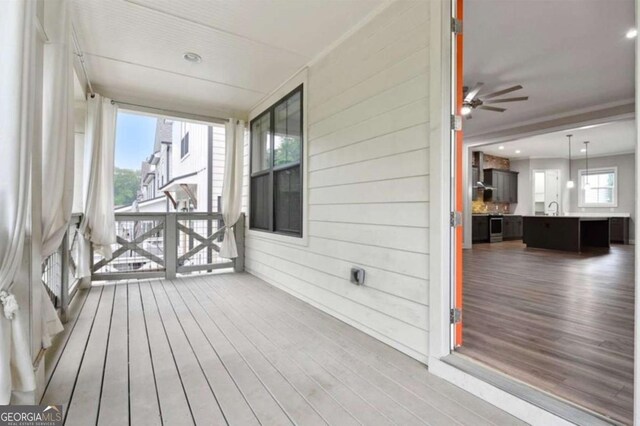 wooden deck featuring a porch, ceiling fan, and sink