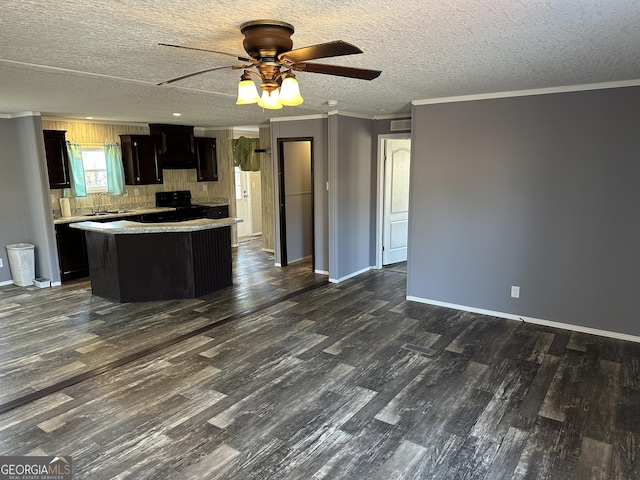 kitchen with ceiling fan, a center island, black stove, and crown molding