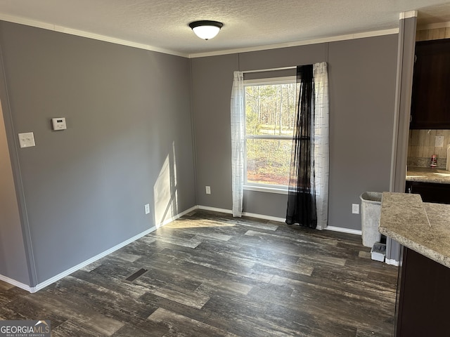 unfurnished dining area with a textured ceiling, dark hardwood / wood-style floors, and ornamental molding