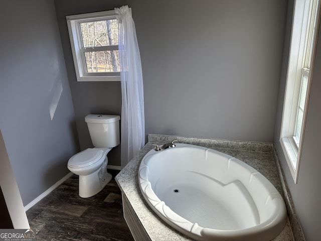 bathroom featuring toilet and a tub to relax in