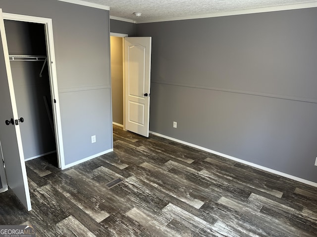 unfurnished bedroom featuring a textured ceiling, crown molding, a closet, and dark hardwood / wood-style floors