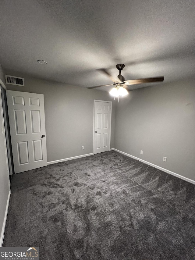 unfurnished bedroom with dark colored carpet, ceiling fan, and a textured ceiling