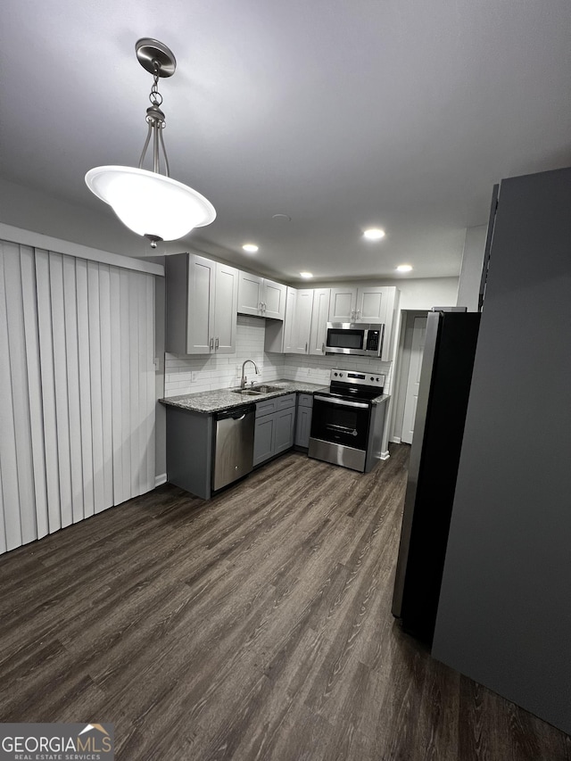 kitchen featuring dark wood-type flooring, sink, hanging light fixtures, and appliances with stainless steel finishes