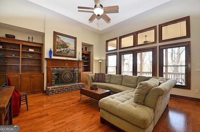 living room with dark hardwood / wood-style floors, ceiling fan, a fireplace, and built in features