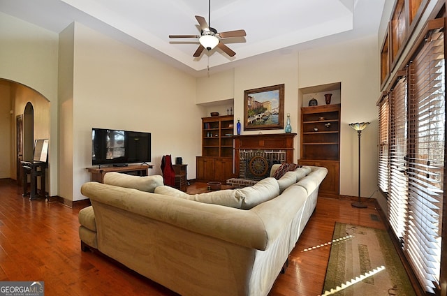 living room featuring built in shelves, dark hardwood / wood-style floors, a fireplace, and a wealth of natural light