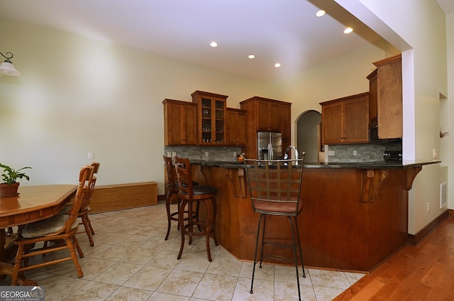 kitchen featuring stainless steel fridge, kitchen peninsula, and a kitchen bar