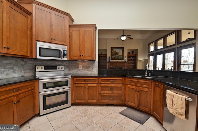 kitchen featuring tasteful backsplash, stainless steel appliances, sink, and dark stone countertops