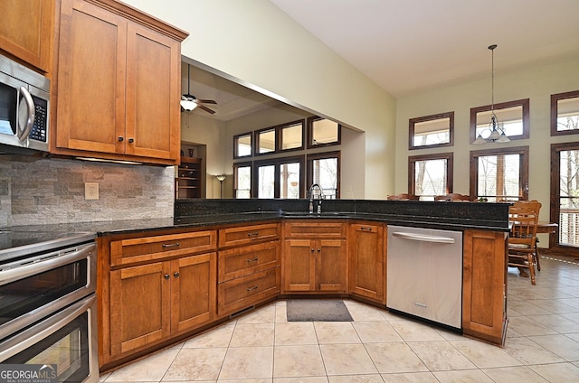 kitchen featuring stainless steel appliances, kitchen peninsula, decorative backsplash, and light tile patterned floors