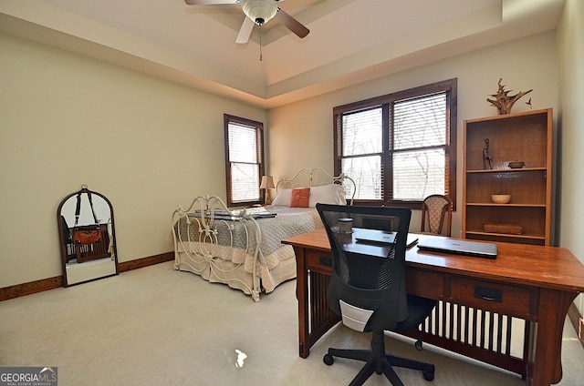 bedroom with light colored carpet, ceiling fan, and a tray ceiling