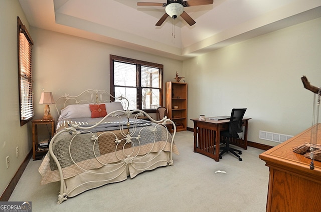 bedroom featuring light carpet, a raised ceiling, and ceiling fan