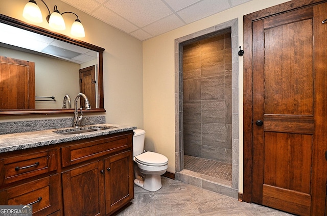 bathroom featuring vanity, tiled shower, a paneled ceiling, and toilet