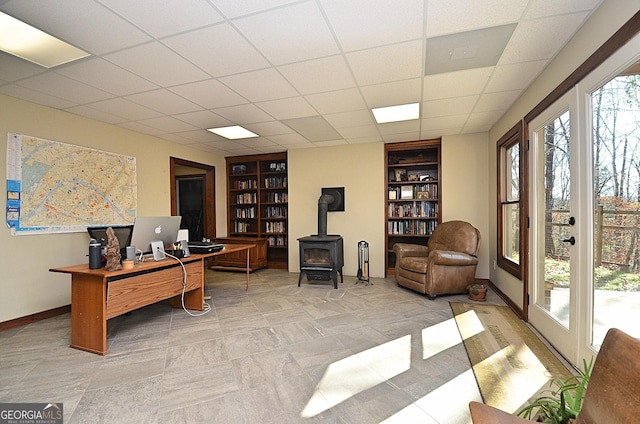 office space with a wood stove, a paneled ceiling, and built in features