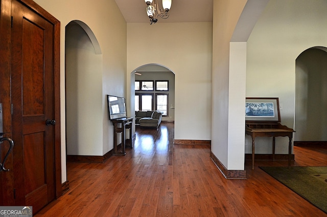 interior space featuring a notable chandelier, a towering ceiling, and dark hardwood / wood-style floors