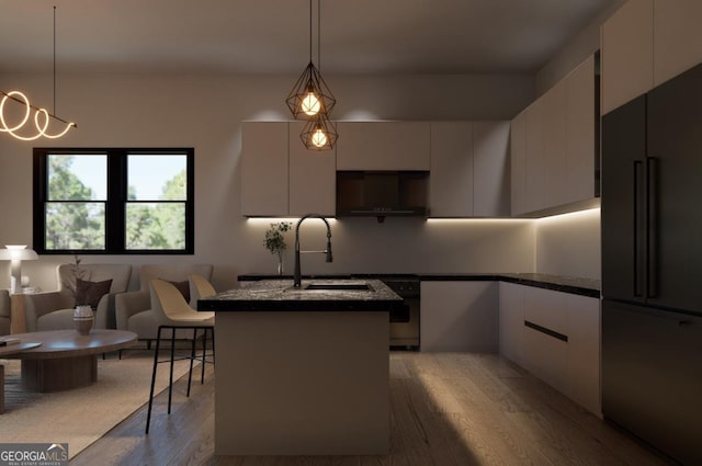 kitchen featuring sink, hanging light fixtures, a kitchen island with sink, high end fridge, and white cabinets