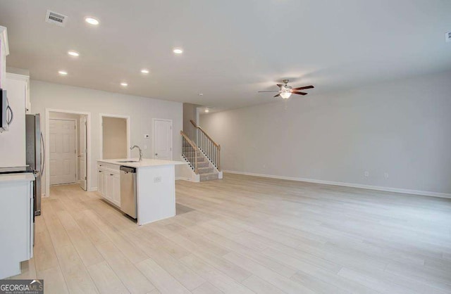 kitchen with ceiling fan, dishwasher, light hardwood / wood-style floors, a center island with sink, and white cabinets