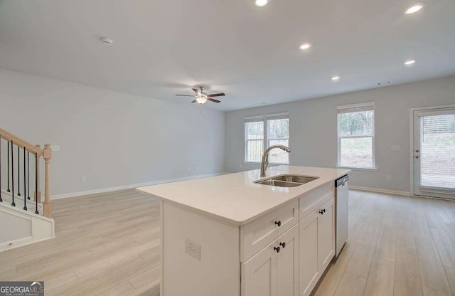 kitchen with dishwasher, a center island with sink, sink, ceiling fan, and white cabinetry