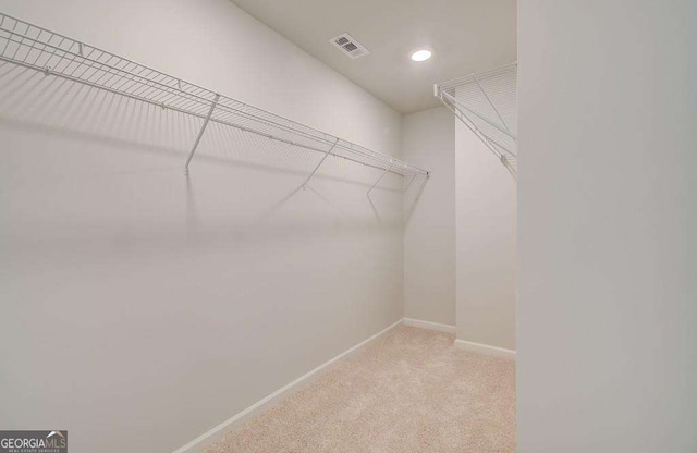 walk in closet featuring light colored carpet