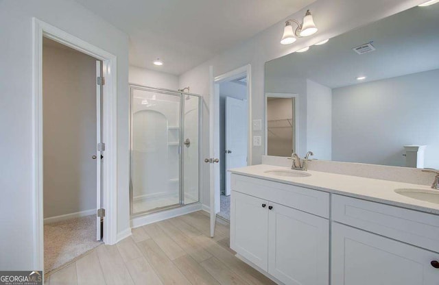 bathroom with hardwood / wood-style floors, vanity, and a shower with shower door