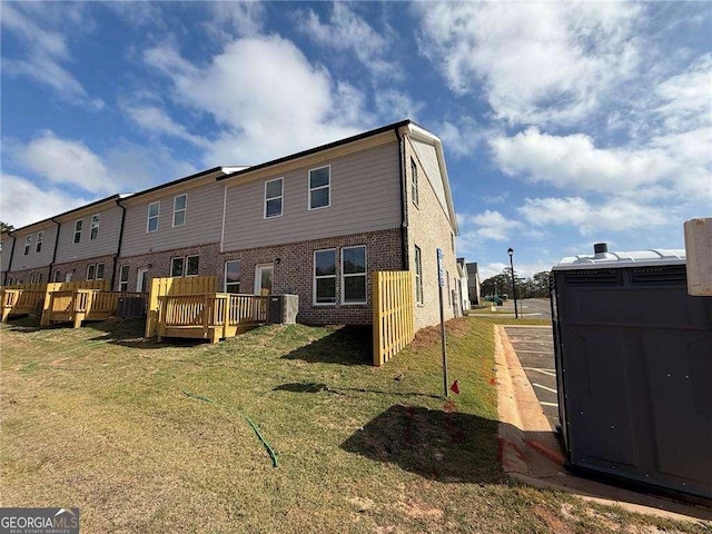 back of property with a lawn and a deck