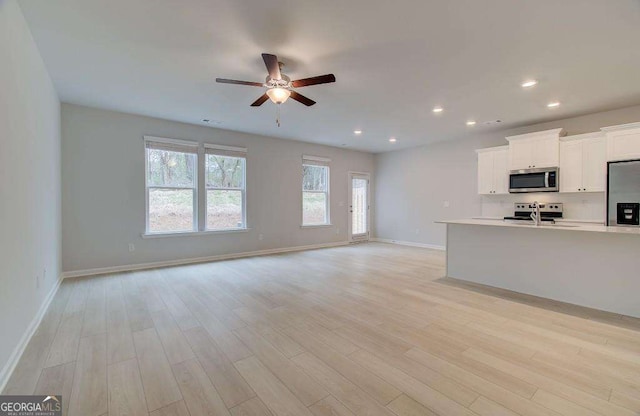 kitchen featuring ceiling fan, white cabinets, light hardwood / wood-style floors, and appliances with stainless steel finishes