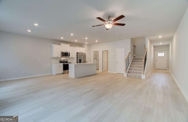 unfurnished living room featuring ceiling fan and light hardwood / wood-style floors