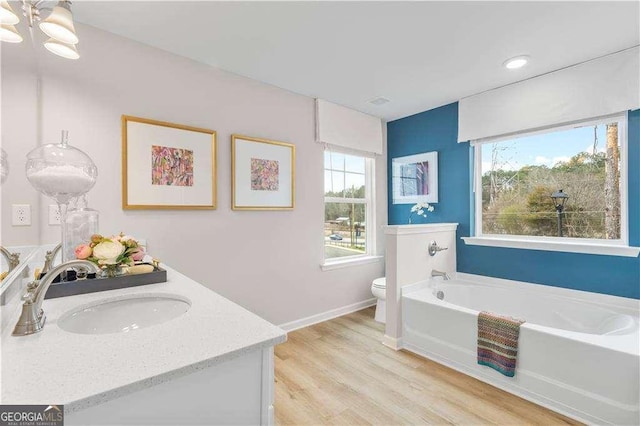 bathroom featuring a bathtub, vanity, hardwood / wood-style flooring, an inviting chandelier, and toilet