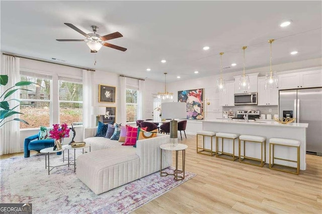 living room featuring light hardwood / wood-style flooring, ceiling fan, and sink