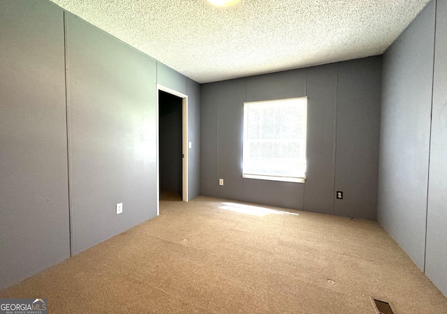 carpeted spare room featuring a textured ceiling