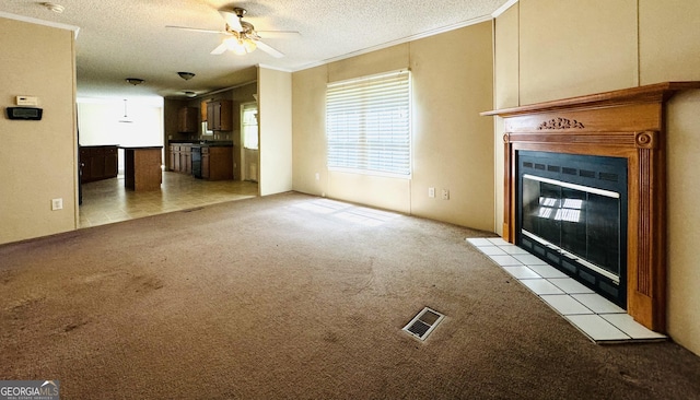 unfurnished living room with ceiling fan, light colored carpet, a textured ceiling, and a tile fireplace