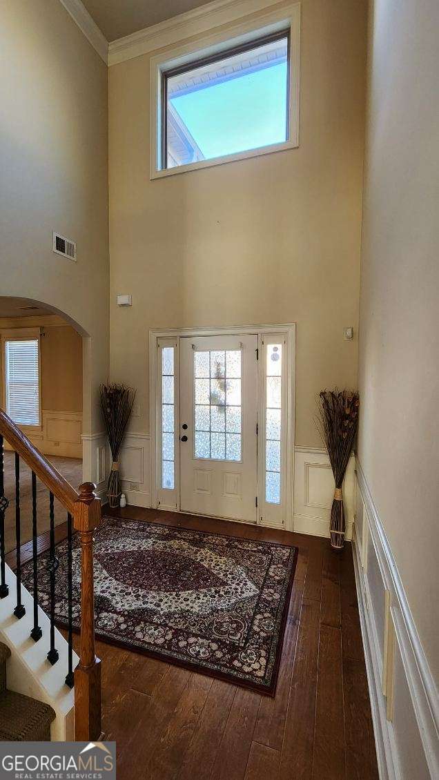 foyer with crown molding, a towering ceiling, and hardwood / wood-style flooring