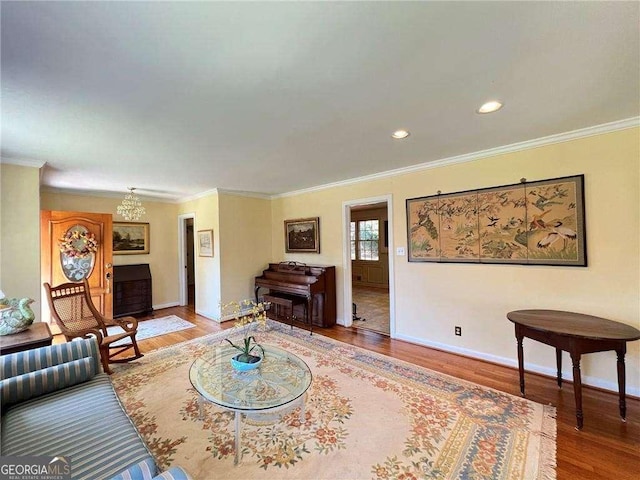 living room featuring wood-type flooring, crown molding, and an inviting chandelier