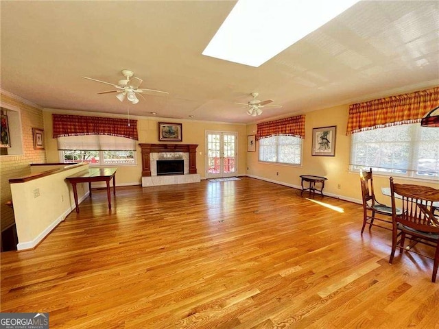 living room featuring ornamental molding, a skylight, ceiling fan, and light hardwood / wood-style floors