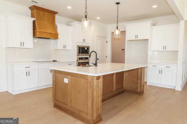 184 Grove Park Unit 11, Senoia, GA 30276 - kitchen featuring appliances with stainless steel finishes, custom exhaust hood, light wood-style floors, decorative backsplash, and a kitchen island with sink