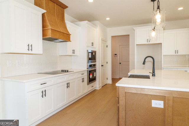 184 Grove Park Unit 11, Senoia, GA 30276 - kitchen with appliances with stainless steel finishes, premium range hood, a sink, light wood-type flooring, and decorative backsplash