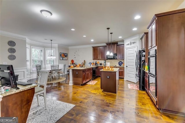 kitchen featuring a center island, decorative light fixtures, crown molding, and black appliances