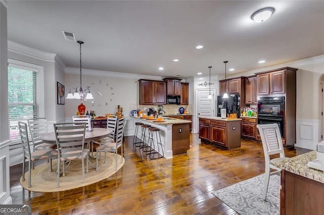 kitchen featuring kitchen peninsula, a breakfast bar, black appliances, pendant lighting, and a chandelier