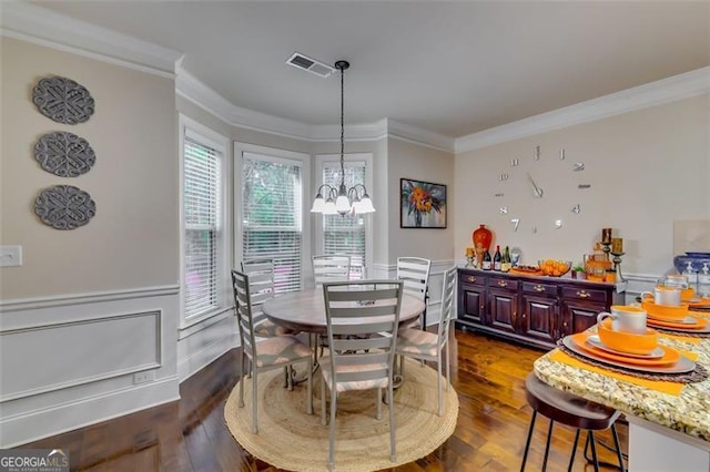 dining area featuring dark hardwood / wood-style floors, crown molding, and an inviting chandelier