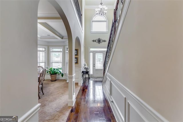 foyer entrance featuring dark carpet, crown molding, and a chandelier