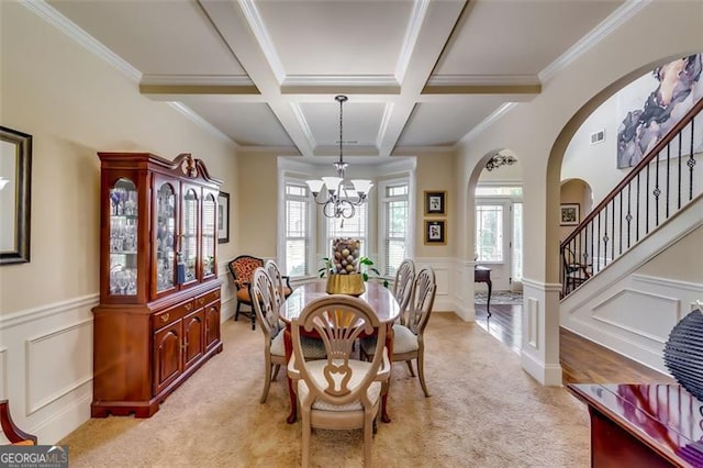 carpeted dining space with beamed ceiling, crown molding, coffered ceiling, and a notable chandelier