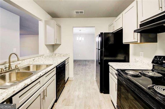 kitchen with light stone counters, sink, white cabinets, and black appliances